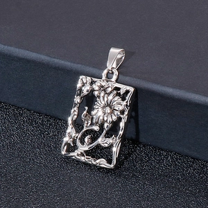 Macro view of a rectangular silver steel pendant with intricate flower and vine engraving