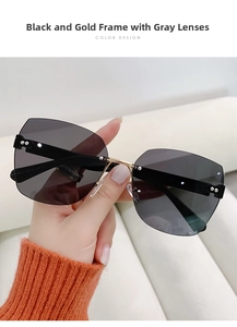 Detail view of rimless sunglasses with black temples and gold bridge shown on hand