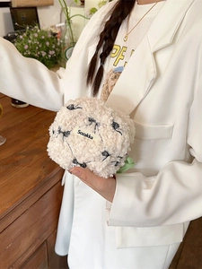 Lambswool makeup bag with bow pattern and zip closure, held in a cafe setting
