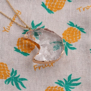 Macro detail of irregular crystal pendant with gold plating on a textured fabric