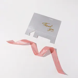 Silver-grey wedding favor box with gold Thank You script and pink ribbon, flat lay view