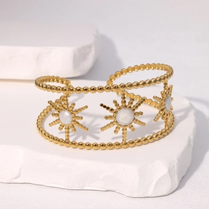 Vintage gold sunflower open cuff bracelet with white gemstones on stone background