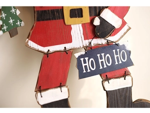 Dettaglio decorativo Babbo Natale in legno con scritta HO HO HO e texture festive