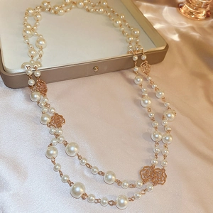 Detailed macro of a long pearl necklace with golden floral hollow metal elements