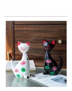 Detail of Nordic hand-painted ceramic cat figurines with red lotus patterns on a glass desk