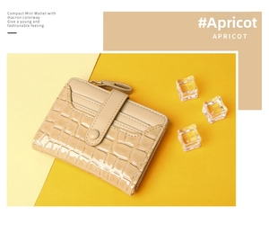Detail view of apricot mini wallet with crocodile texture and metal zipper closure