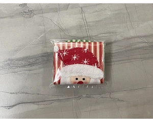 Detail of Santa Claus knitted wine bottle cover in packaging on marble surface