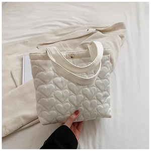 Close-up of white heart-quilted oxford fabric tote bag with elegant gold metal buckle
