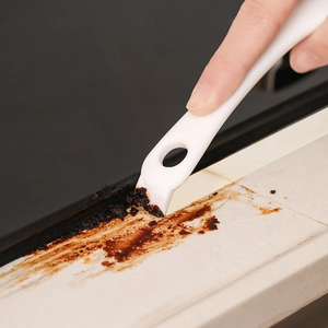 Multipurpose kitchen stove cleaning scraper removing burnt residue from gap