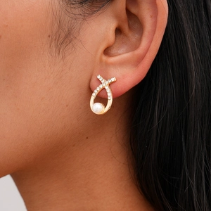 Detailed view of elegant gold-tone flower earring with pearls and sparkling crystals