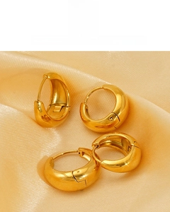 Detail of 18K vacuum plated golden hoop earrings on elegant champagne silk fabric