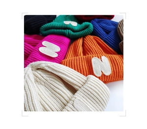 Close-up of knit texture and N logo patch on colorful winter beanies for children
