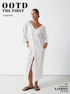 Detail of white cotton maxi dress featuring V-neckline and high front slit design
