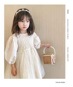 Détail de la robe crème à manches bouffantes avec panier en paille et bandeau en perles