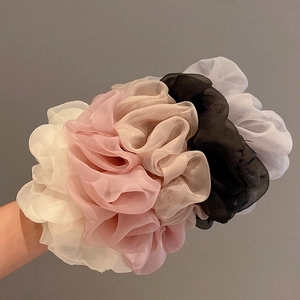 Detailed view of assorted soft chiffon scrunchies in five pastel colors on a model's arm