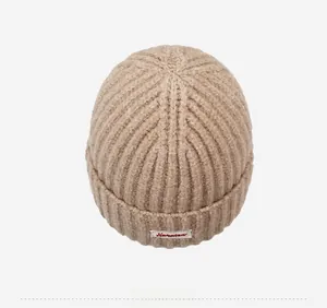 Vista dall'alto di un berretto in maglia beige con trama a coste e etichetta logo