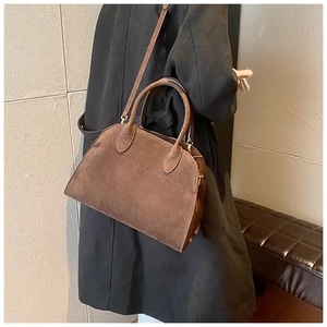 Dettaglio di una borsa tote in pelle scamosciata marrone con doppi manici e tracolla lunga