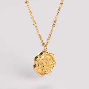 Macro shot of gold floral embossed pendant on a delicate chain with vintage French style