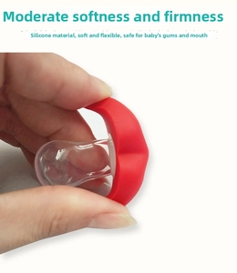 Hand squeezing soft red lip baby pacifier to show flexible food-grade silicone texture