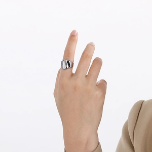 Close-up of a polished silver lava-style irregular textured titanium steel ring on finger