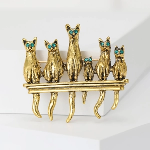 Detail of vintage gold alloy brooch featuring six cats with green crystal eyes on a beam