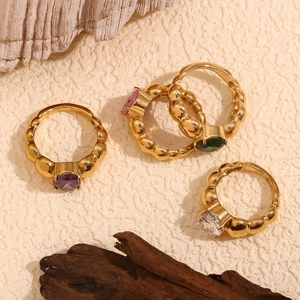Close-up of gold beaded stackable rings with purple, pink, green, and clear crystals