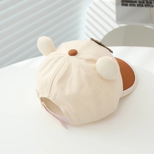 Détail d'une casquette enfant beige avec oreilles d'ours 3D et visière courbée marron