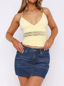 Detalle de top halter amarillo con encaje de retales y diseño de cintura calada