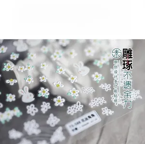 Detail of 5D embossed nail stickers featuring white daisies and cute cartoon rabbits