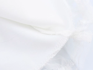 Macro shot of white dress fabric showing hem stitching and transparent lace details