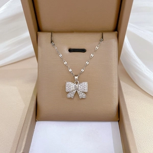 Détail du pendentif nœud étincelant sur chaîne argentée dans son écrin beige