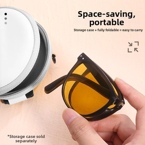 Macro shot of compact folded sunglasses with yellow lenses next to a grey travel case