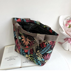 Detail view of large canvas tote bag featuring interior pockets and colorful leaf print