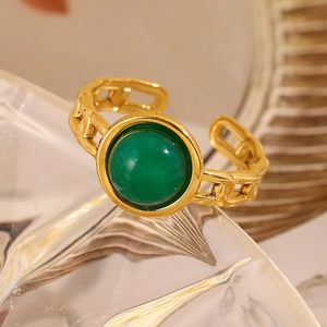 Macro detail of 18K gold plated chain ring with a vintage green round gemstone inlay