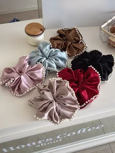 Flat lay of large satin scrunchies with pearl edges in six assorted pastel colors