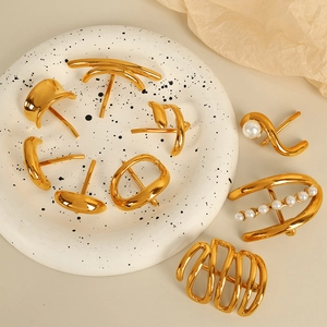 Elegant gold-plated non-pierced ear cuffs with pearls on a decorative ceramic tray