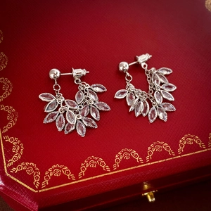 Macro shot of silver leaf zircon earrings with tassels resting on a red jewelry box