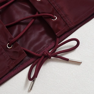 Macro detail of wine red PU leather top with silver metal eyelets and criss-cross laces