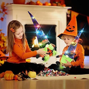 Close-up of glowing Halloween gnomes with purple and orange hats near a cozy fireplace