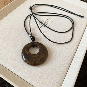 Detailed close-up of a vintage brown resin donut pendant with gold sand textures