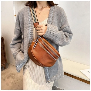 Close-up of brown litchi texture leather waist bag with a wide striped fabric strap