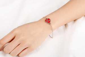 Detail of silver stainless steel adjustable bracelet with red heart Love charm on wrist