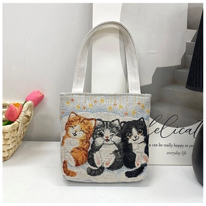 Detailed view of three colorful embroidered cats and stars on a beige canvas tote bag
