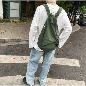 Outdoor shot of an army green canvas crossbody bag with multiple zipper pockets