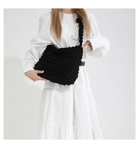 Macro detail of black bubble texture fabric on a large capacity pleated shoulder bag