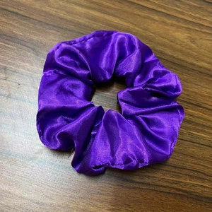 Detail of purple satin LED scrunchie with glowing lights on a wooden surface