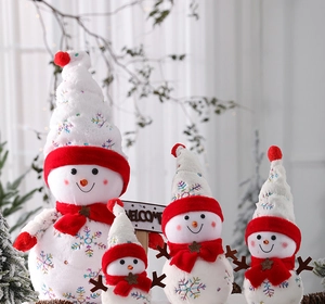 Dettaglio di quattro pupazzi di neve natalizi in peluche con paillettes e cartello Welcome