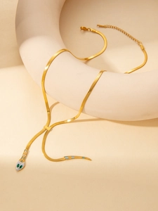 Détail du collier serpent doré en Y avec yeux en pierres vertes et accents en émail