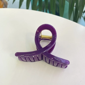 Détail de la grande pince à cheveux violet foncé en résine avec design croisé Mobius sur blanc