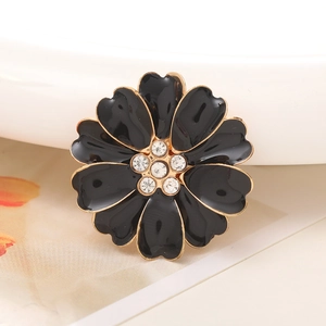 Macro view of black enamel flower charm with golden edges and clear rhinestone center